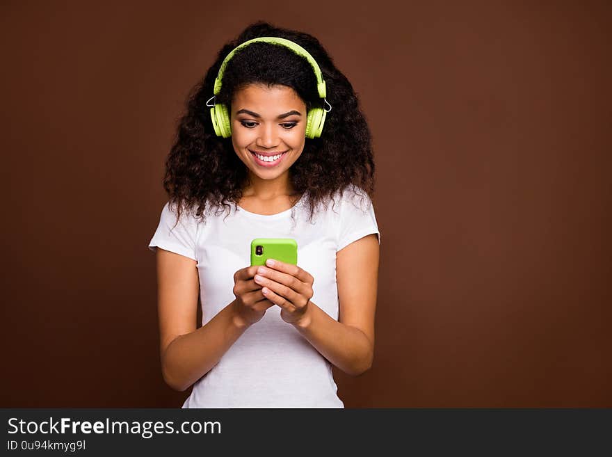 Portrait of positive cheerful afro american girl use cellphone want listen radio melody search online playlist have