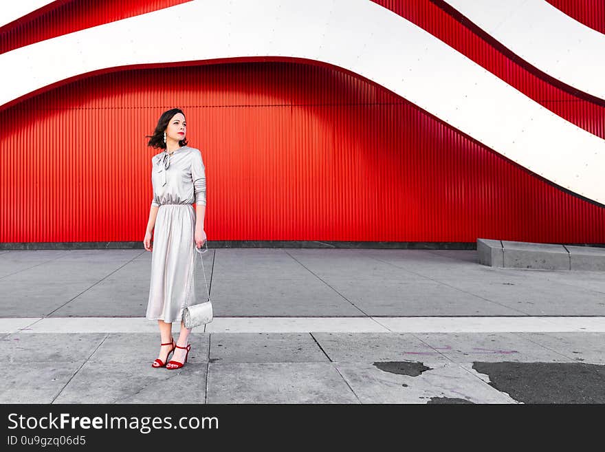 Beautiful glamorous woman in heels at the red wall