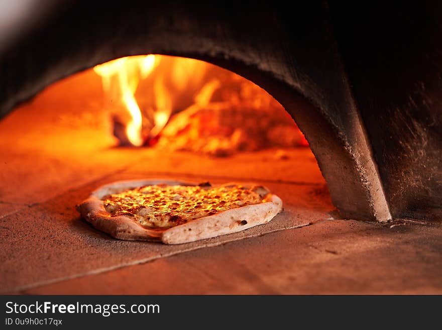 Baked tasty margherita pizza in Traditional wood oven in Naples restaurant, Italy. Original neapolitan pizza. Red hot coal