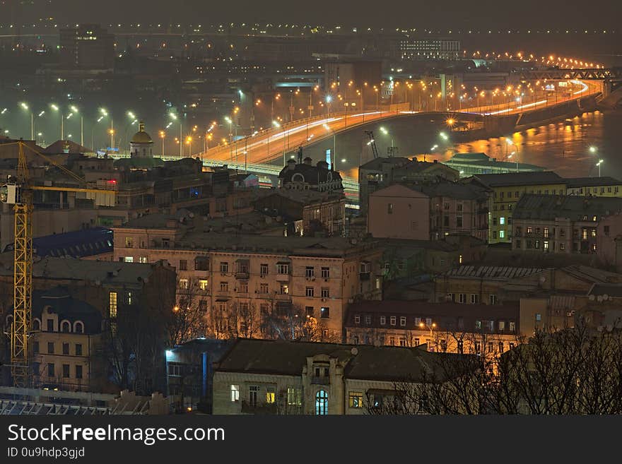 Beautiful night illuminated landscape of Podil. It is one of the oldest neighborhoods of Kyiv. It is located near Dnipro River. Roofs of old buildings and Harbour Bridge in the background. Ukraine