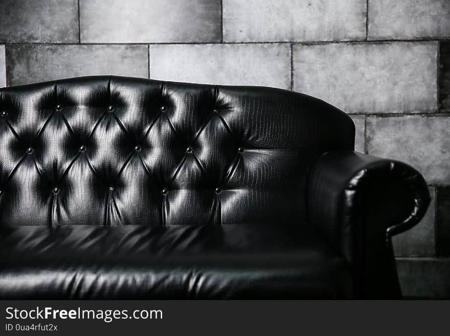 Black Leather Sofa Against A Gray Stone Wall