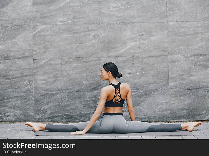 Pretty lady training in a summer city. Brunette doing yoga. Gitl in a sportsuit. Pretty lady training in a summer city. Brunette doing yoga. Gitl in a sportsuit