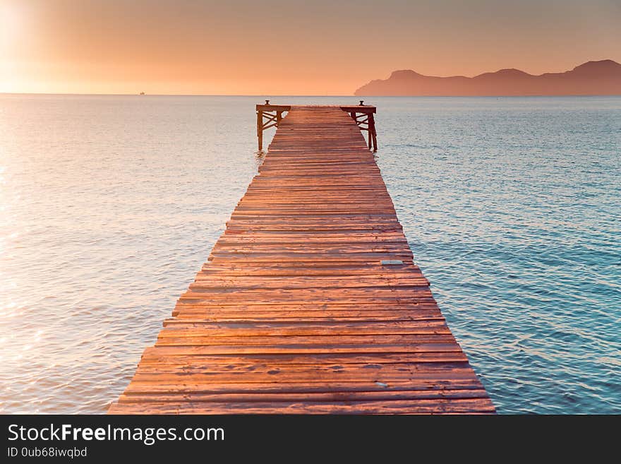 Warm Morning Light In Summer Vacation Holiday Resort. Pier In Orange Sunrise Colors