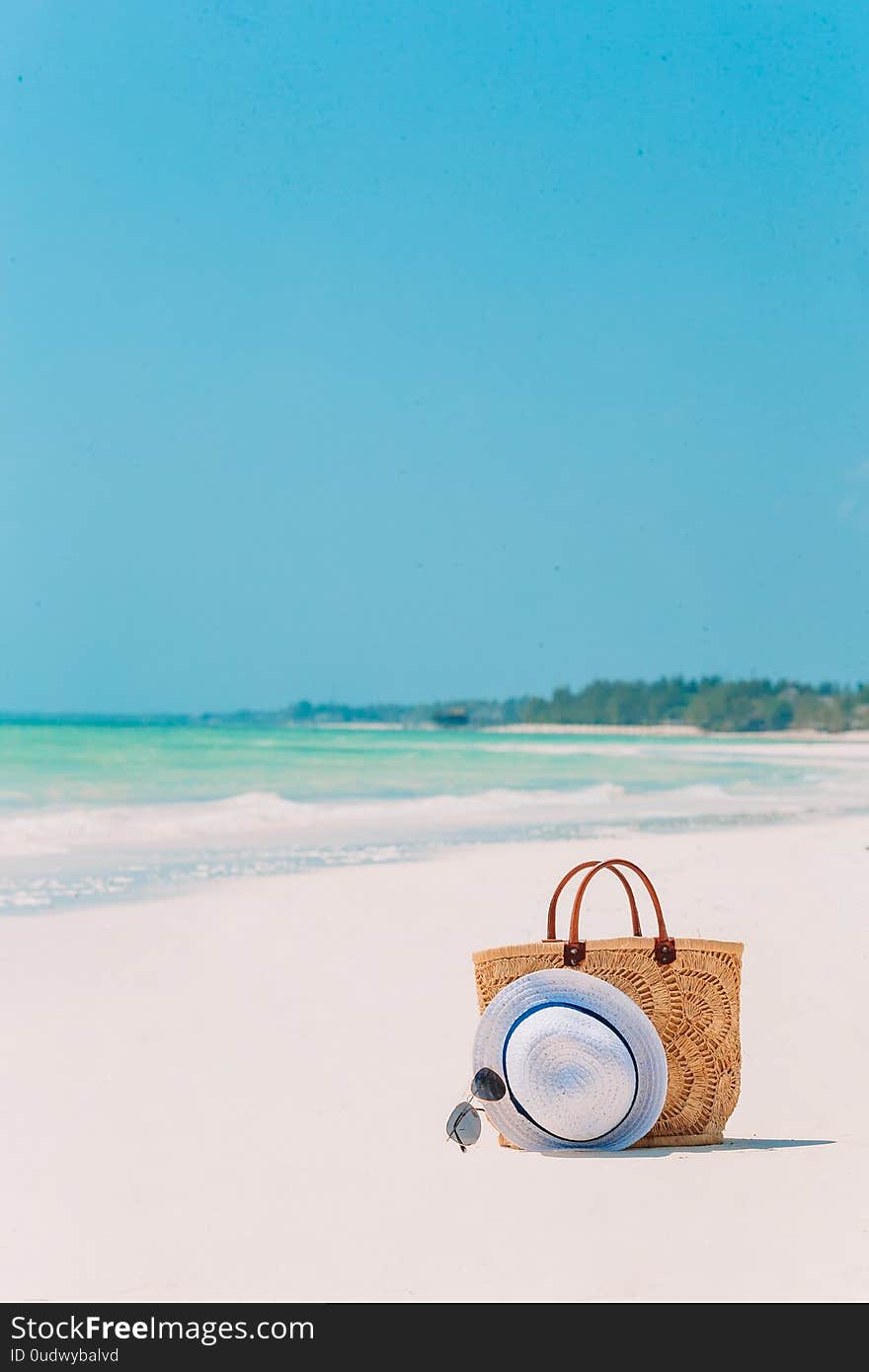 Beach accessories - bag, straw hat, sunglasses on white beach. Beach accessories - bag, straw hat, sunglasses on white beach