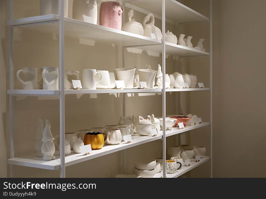 Ceramic dishes for painting on shelves in a craft workshop. Different dishes for every taste, for various events.