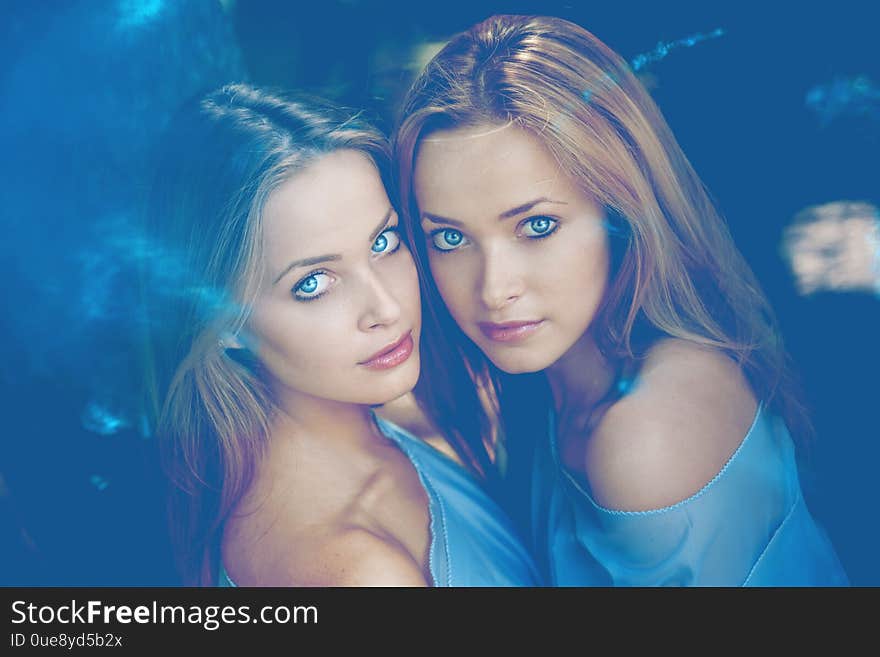 Two girls, women models in blue. Two twins in the forest.