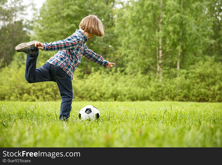 Sports Kid. Baby playing soccer ball in the park. Children play football. Family leisure.