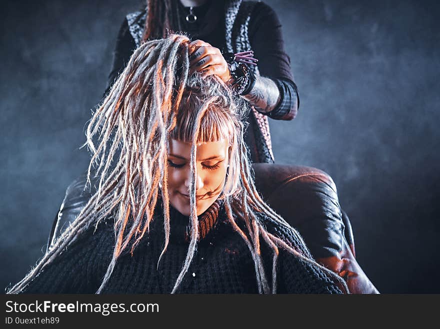 Young pensive women got new freaky hairstyle from dreadlocks master. Young pensive women got new freaky hairstyle from dreadlocks master.