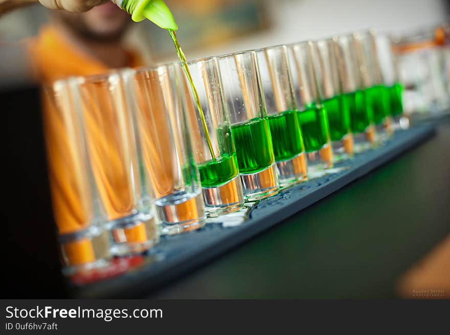 Tall glasses with green alcohol on the gray bar in the bar. The work of the bartender