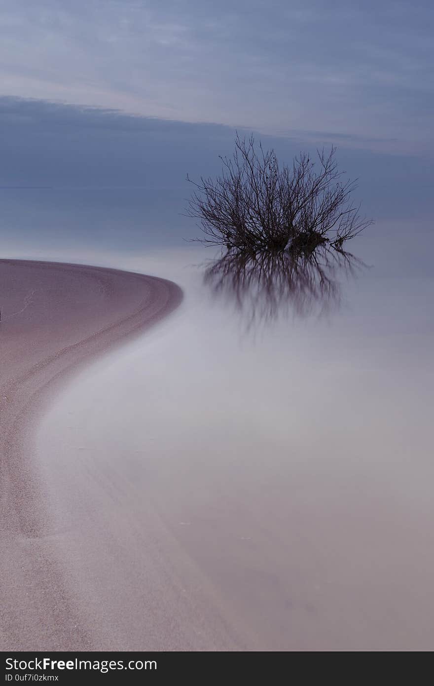 River. Sandy shore. Calm water. Sunset. Cloudy sky