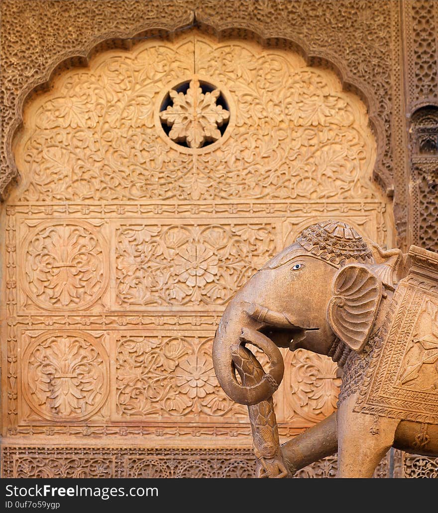 Ancient sandstone bas-relief at Nathmal Ki haveli and elephant statue guard on the street in Jaisalmer, Rajasthan, India. Ancient sandstone bas-relief at Nathmal Ki haveli and elephant statue guard on the street in Jaisalmer, Rajasthan, India