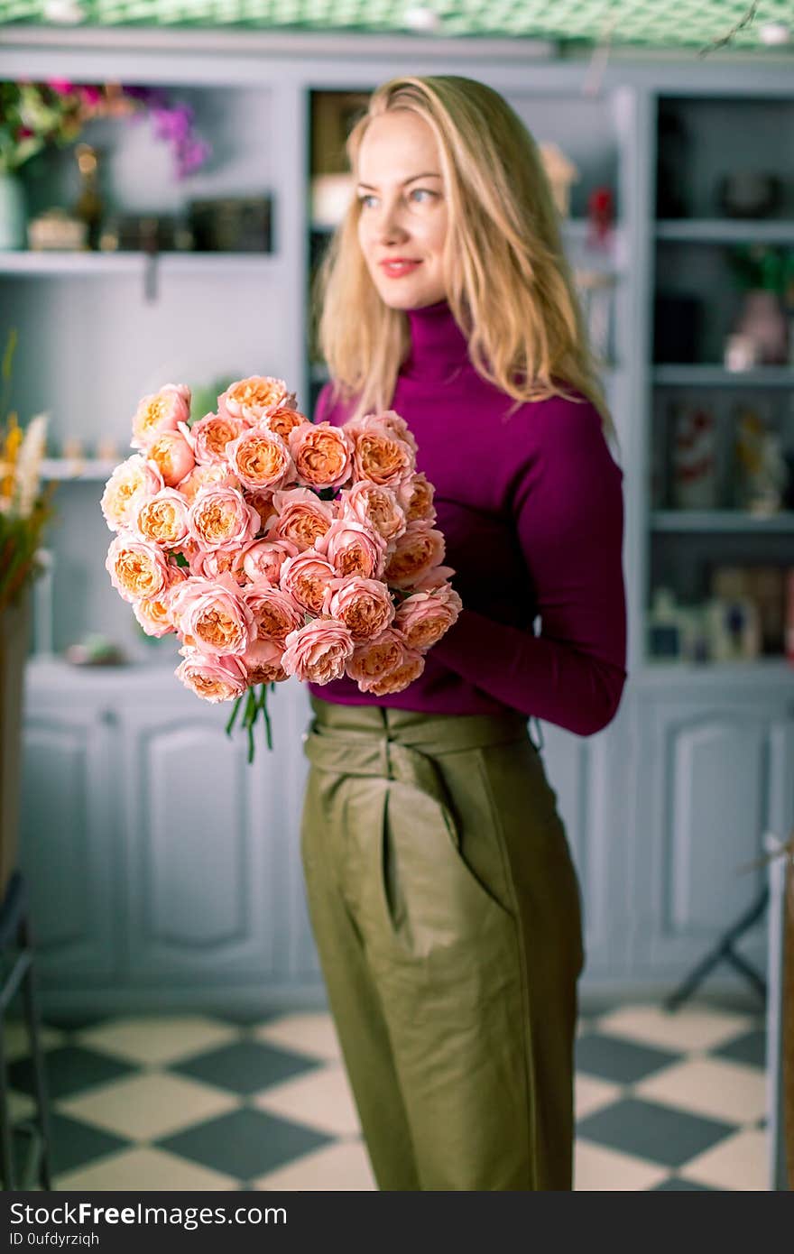 Female florist creating beautiful bouquet in flower shop, close up