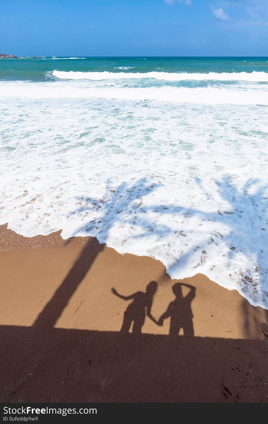 Pristine tropical beach with shadows from palm trees and happy couple on the sand