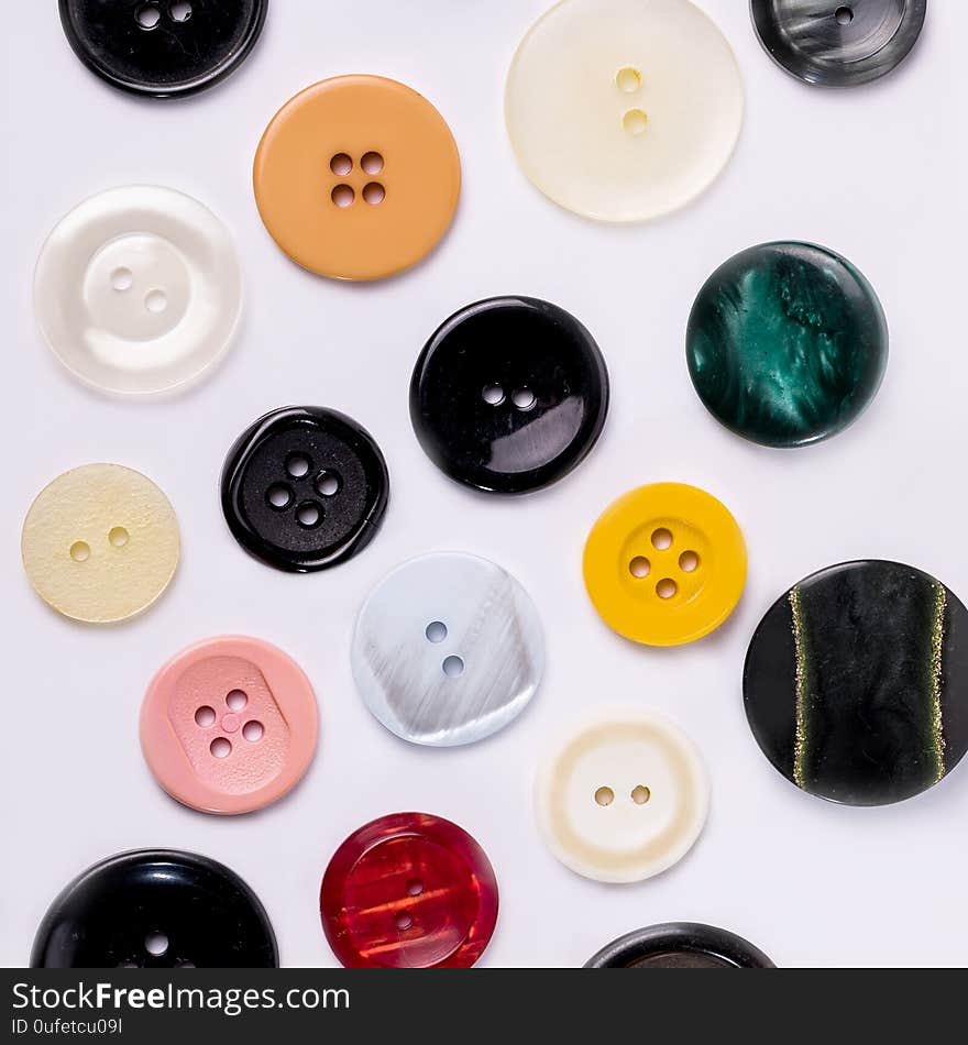 A collection of different spare clothing buttons. Different buttons on a white table for sewing clothes.