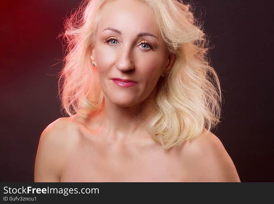 Portrait old woman in colorful bright lights. red and gold color, dark maroon background