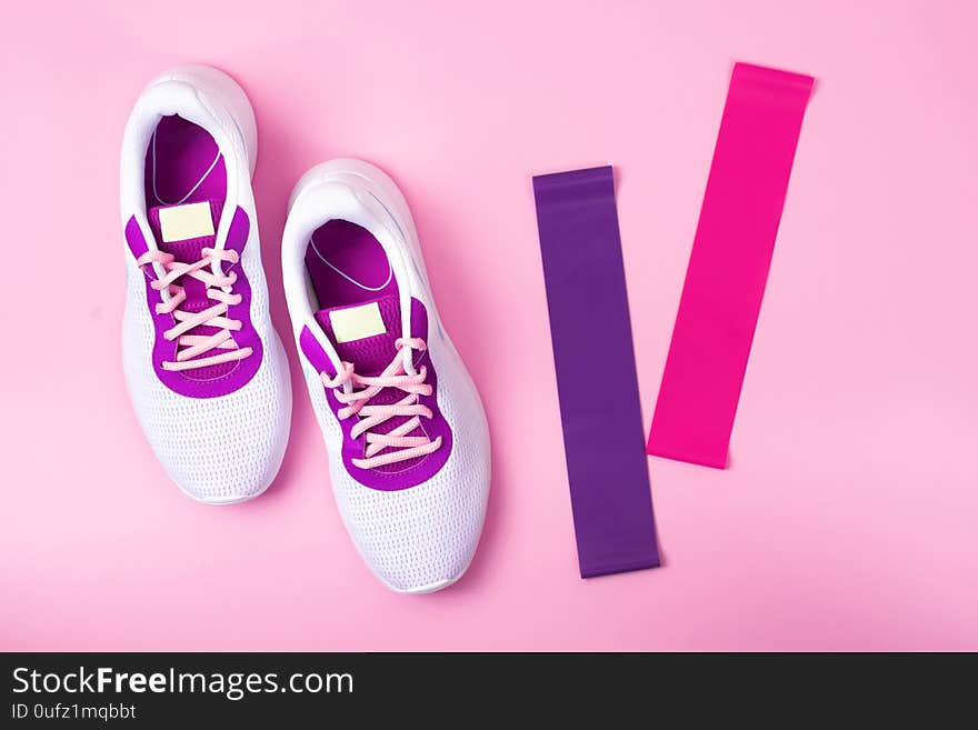 Women`s white sneakers on a pink background. The view from the top