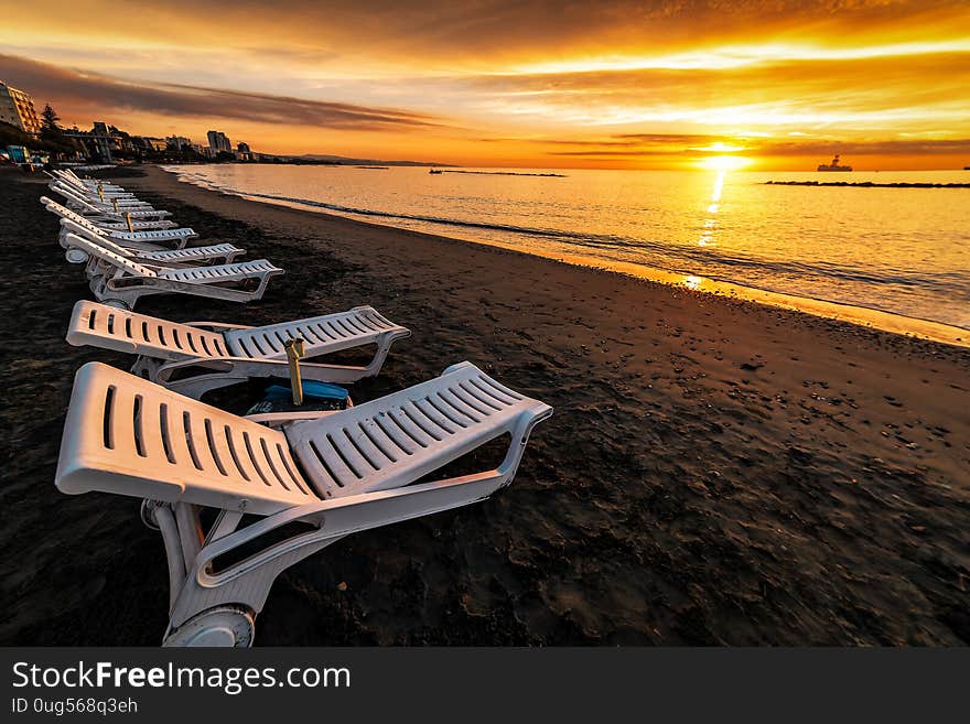 Row sun beds on beautiful sunrise over the sea