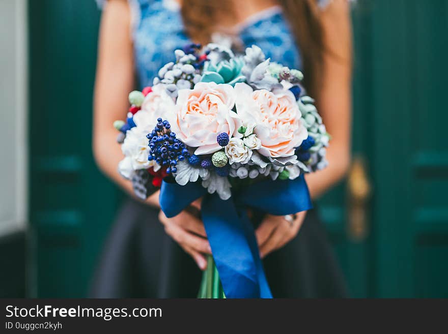 Elegant female hands holding handmade flowers made from Japanese polymer clay. They look like a real wedding bouquet