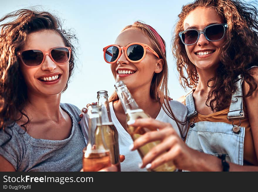 Three Young Women Standing And Clinking Beer Together