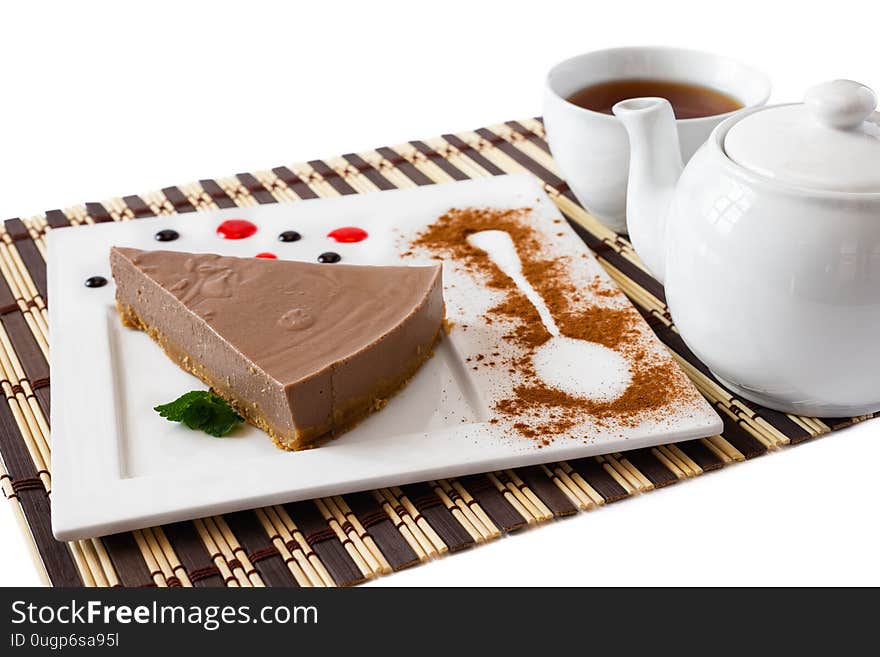 Portion of chocolate cheesecake served on a square plate and bamboo mat with black tea. Portion of chocolate cheesecake served on a square plate and bamboo mat with black tea