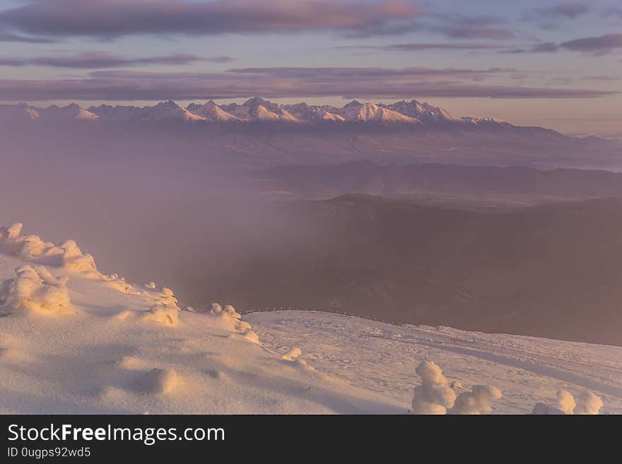 Fog in winter partially obscures the view of the high mountains that touch the clouds. Fog in winter partially obscures the view of the high mountains that touch the clouds