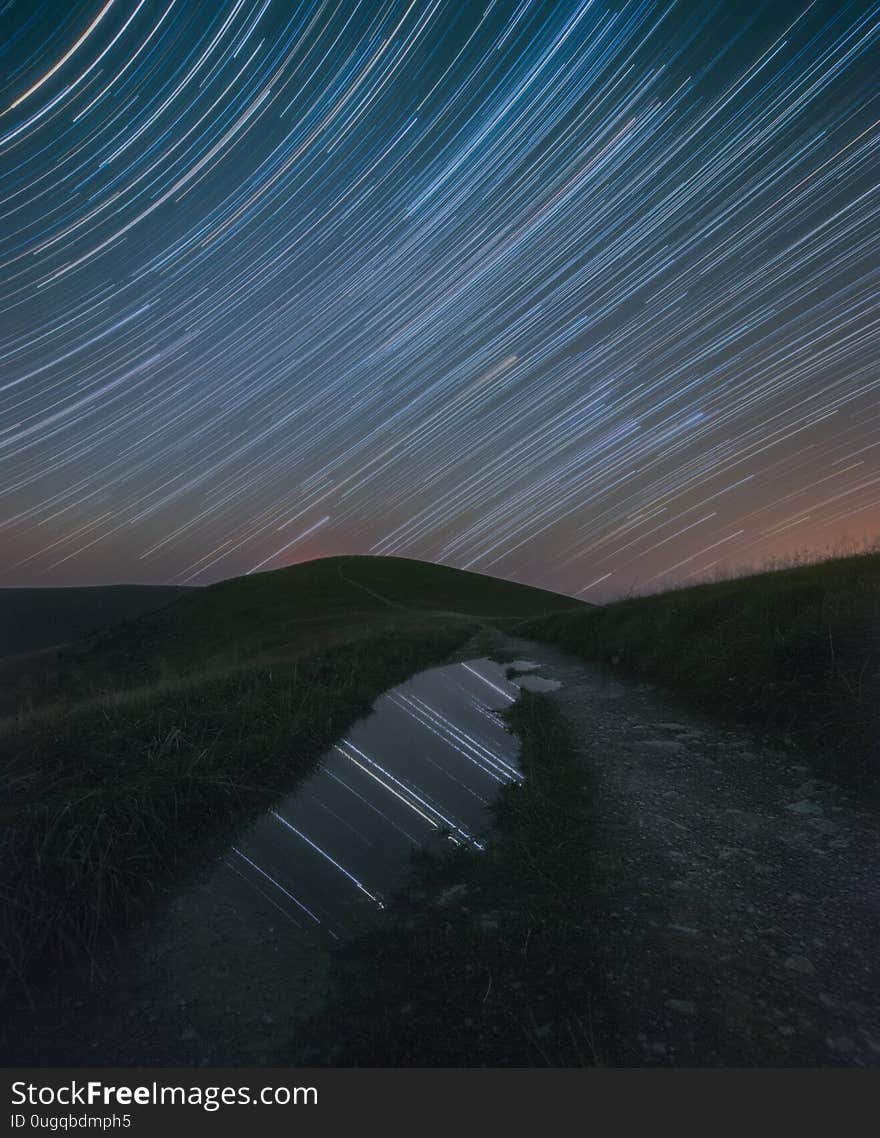 Star trails mirrored in a puddle on a mountain road. Star trails mirrored in a puddle on a mountain road