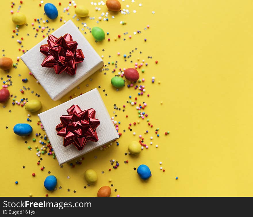 Happy birthday or party background.  Flat Lay wtih gifts, confetti and candy on yellow background. Top View.  Copy space