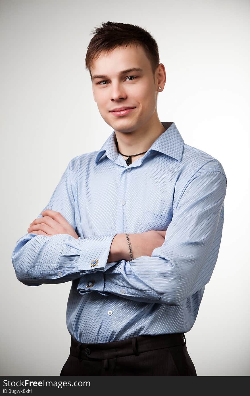 Guy with short brown hair dressed in blue shirt and black pants, posing with arms crossed on his chest. Isolated on white background. Guy with short brown hair dressed in blue shirt and black pants, posing with arms crossed on his chest. Isolated on white background