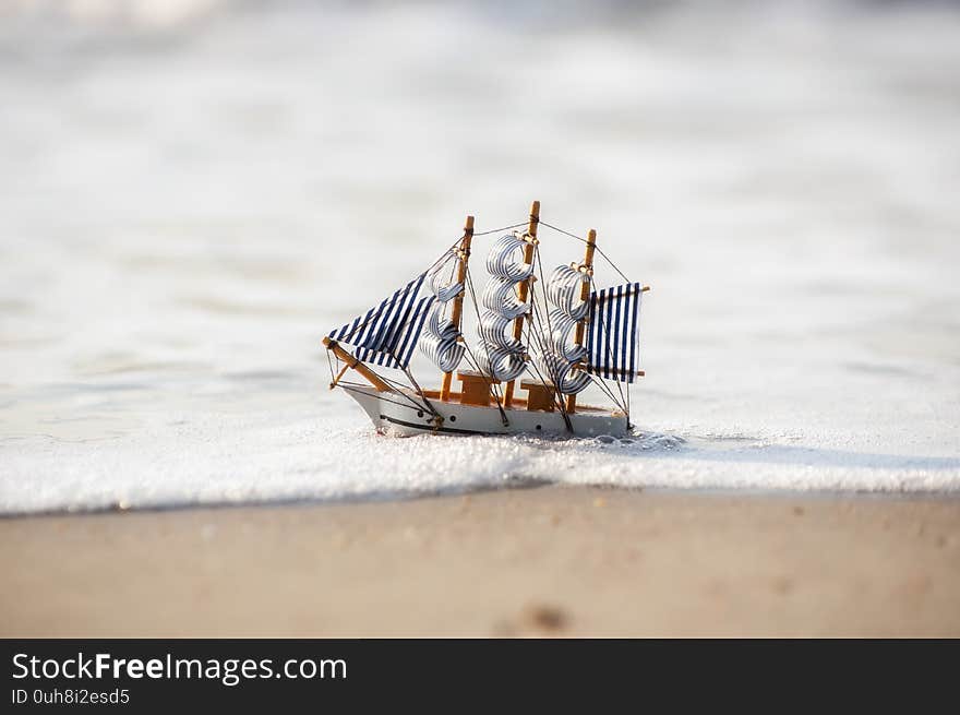 Vintage sailboat model on beach sand, discovery concept