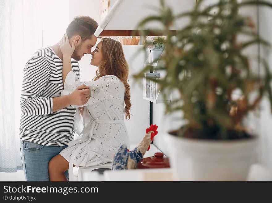 Cute couple in a kitchen. Lady in a white blouse. Pair at home. Cute couple in a kitchen. Lady in a white blouse. Pair at home