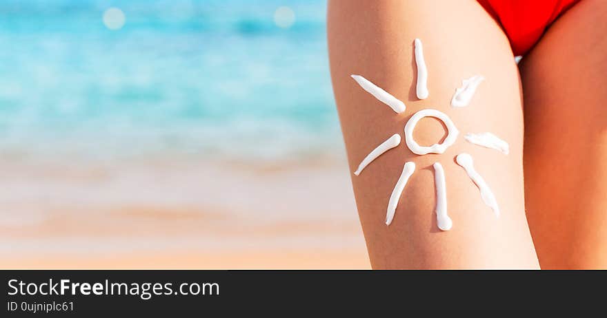 Sun Shape Is Made Of Sunscreen On Woman`s Leg At The Sea Background