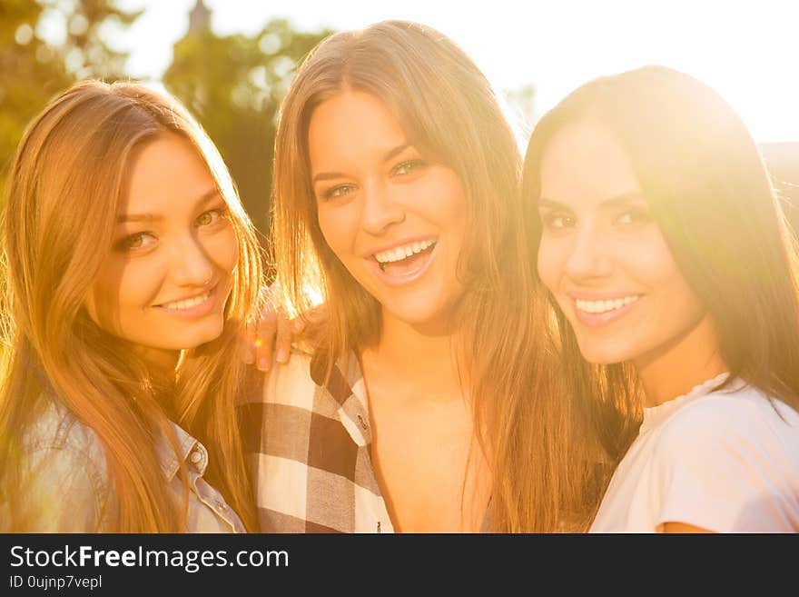 Three Smiling Joyful Girlfriends Hugging And Looking At Camera