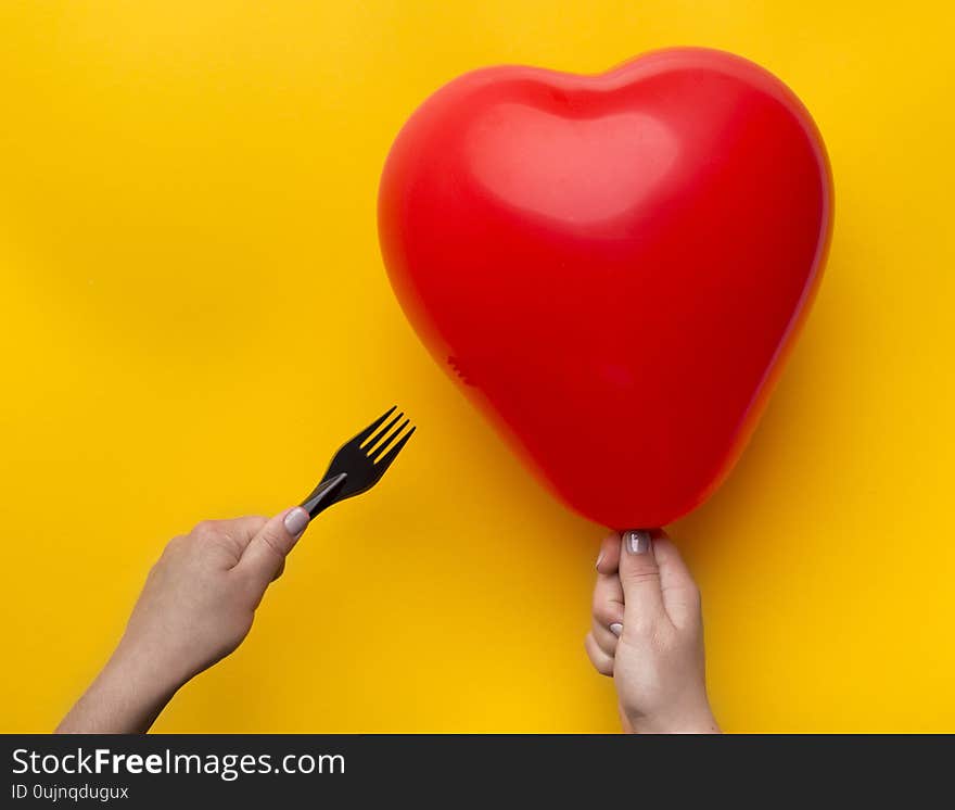 Relationship crisis, break up. Woman holding red heart balloon and pinned with scissors over yellow background