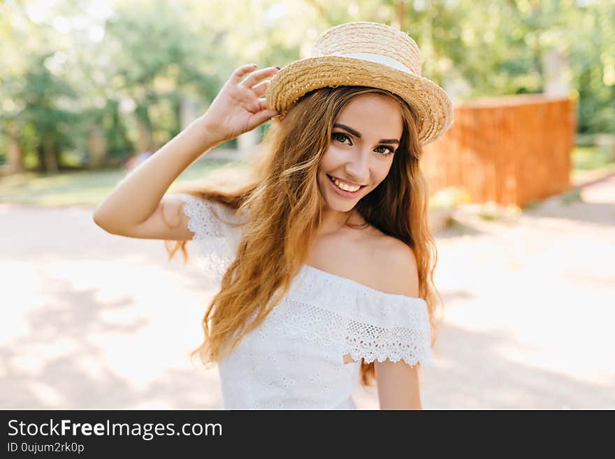 Close-up portrait of inspired young lady with beautiful eyes holding straw hat. Romantic fair-haired girl with pale skin