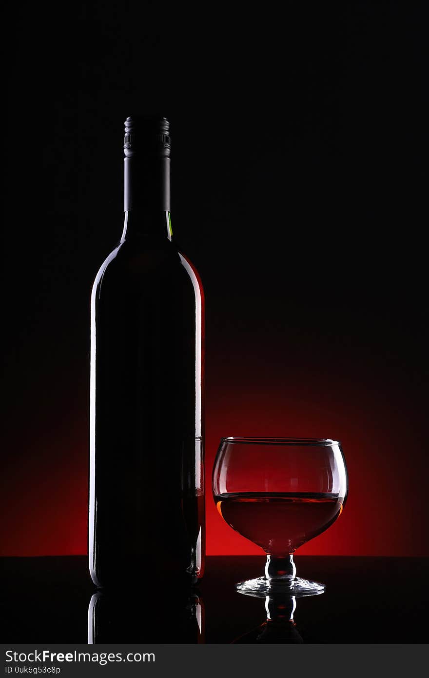 Wine Bottle and Glass on Dark Red Background