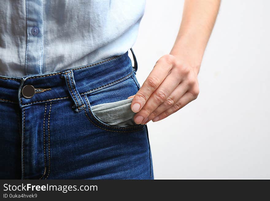 Woman showing empty pocket on light background, closeup