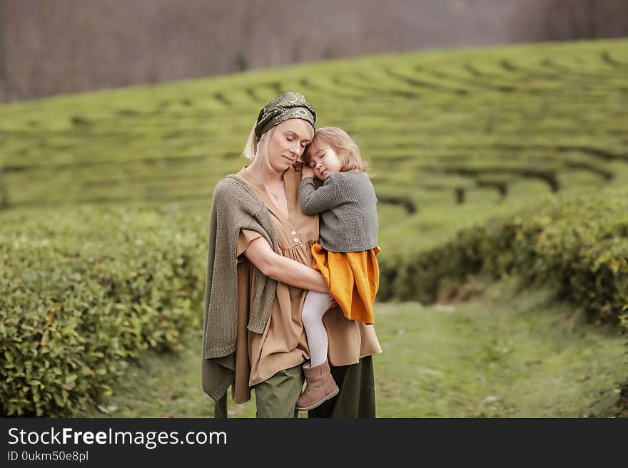 Mom Cuddles Baby Outdoors. A women with a child walking on a tea plantation