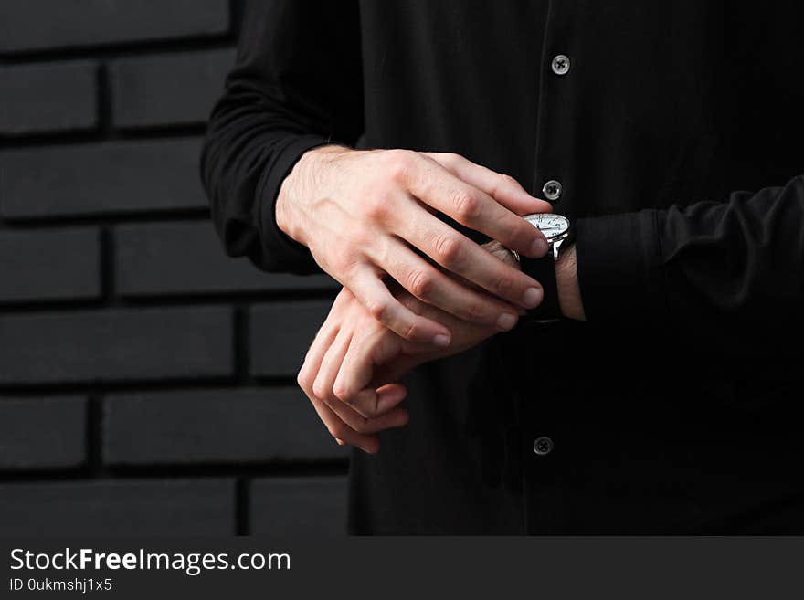 Stylish man with wristwatch near wall checks what hour quality image