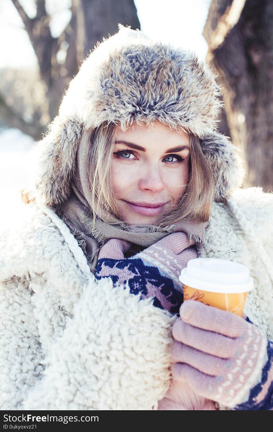 Young pretty teenage hipster girl outdoor in winter snow park having fun drinking coffee, warming up happy smiling, lifestyle people concept close up