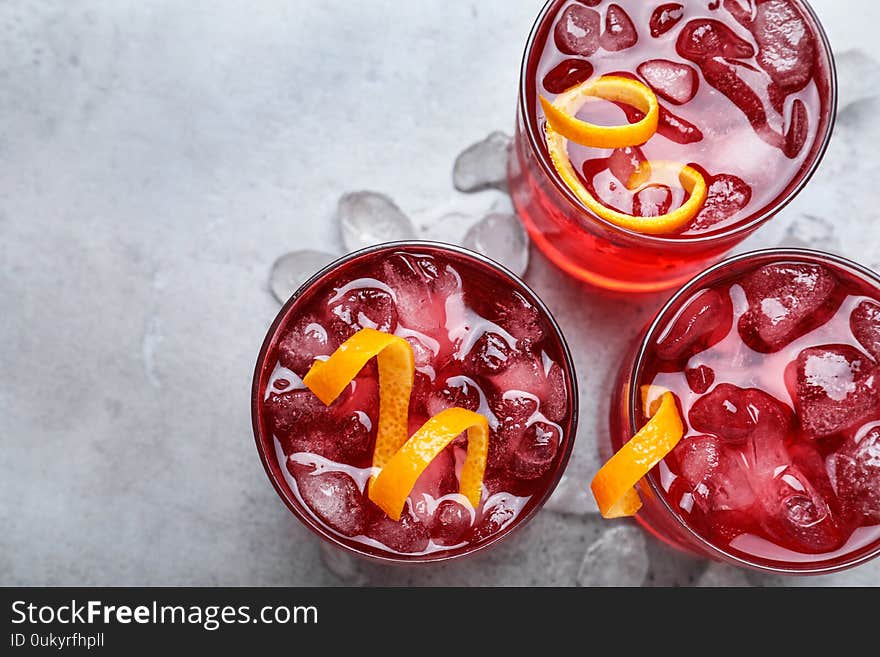 Fresh Negroni cocktails with orange zest on grey table, flat lay