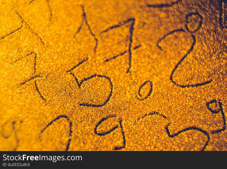 Different numbers painted on brown sand. Numerical background on golden space