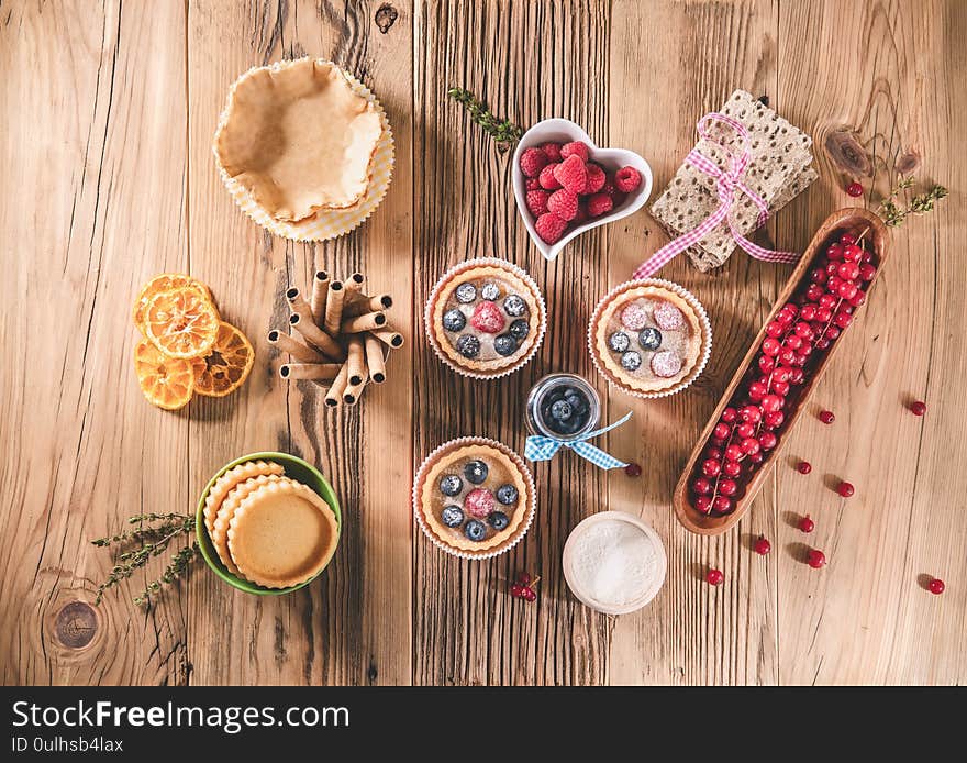 Delicious fresh blueberry and raspberries tartlets on wooden table. Retro concept