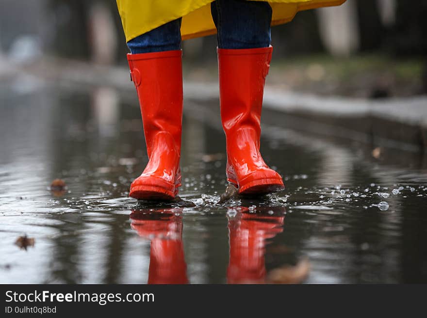 Woman jumping in puddle outdoors on rainy day