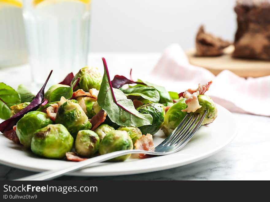 Delicious Brussels sprouts with bacon on table, closeup