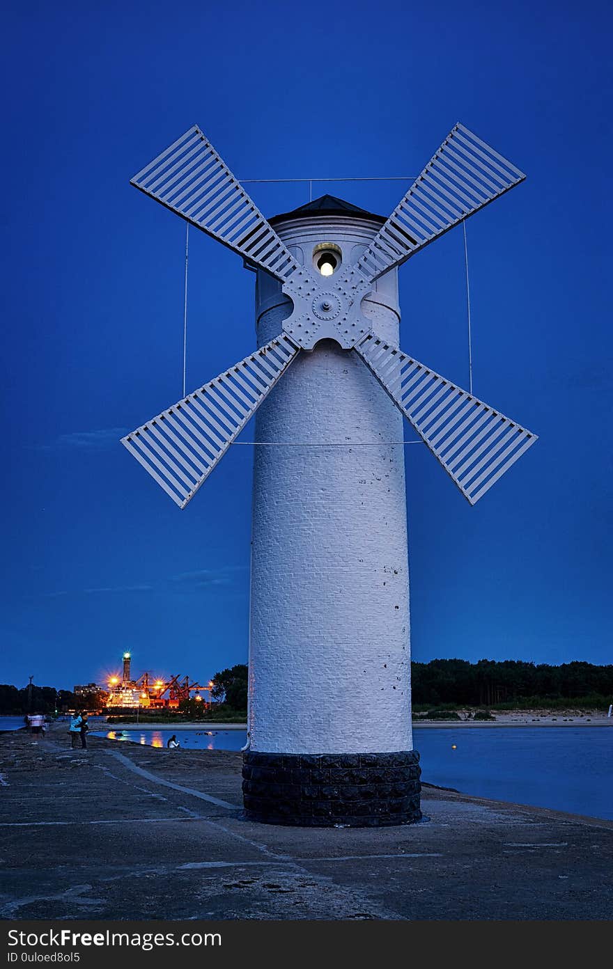 Lighthouse in the evening on the Baltic Sea with windmill wings in Swinemünde. Swinoujscie, Poland.