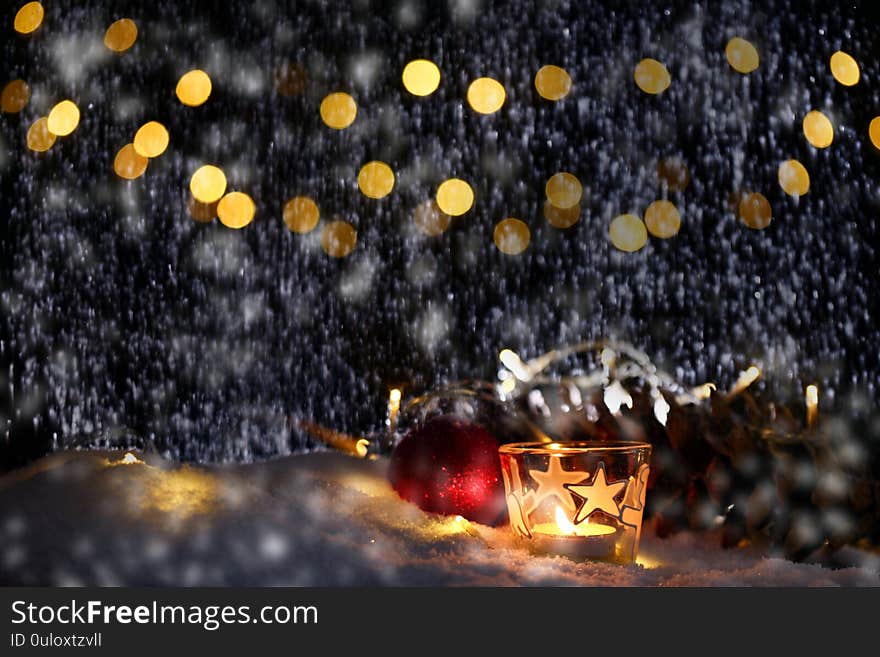 Christmas theme with candles, snow, pine cone and christmas light with pokeh effect