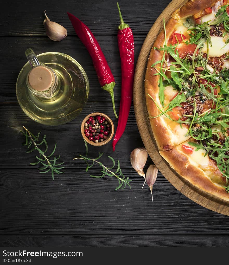 Hot pizza with chicken and arugula on a black wooden background