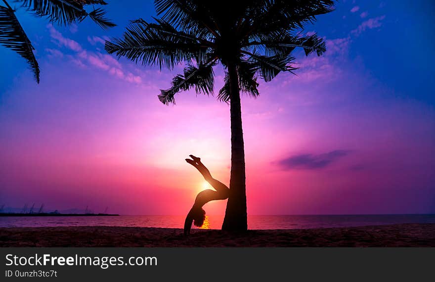 Beautiful young woman practic yoga at the beach. Early morning exercise. Sunrise