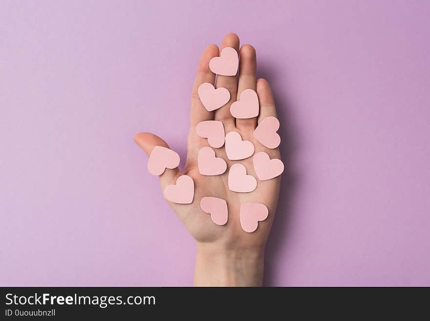 Cropped view of woman holding pink paper hearts on violet background,stock photo. Cropped view of woman holding pink paper hearts on violet background,stock photo