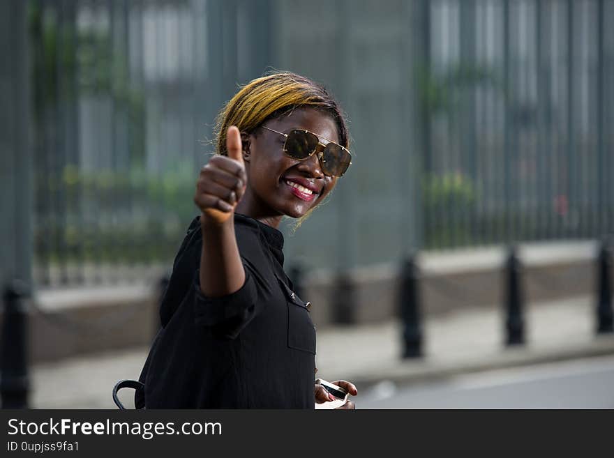 Student with sunglasses walking happy and showing thumb up in the city. Student with sunglasses walking happy and showing thumb up in the city